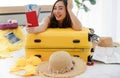 Asian young happy female traveler showing red passport with air tickets leaning on big yellow trolley luggage on bed look at Royalty Free Stock Photo