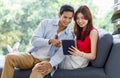 Asian young happy lovely boyfriend and girlfriend couple in casual outfit sitting smiling on cozy sofa couch in living room using