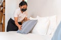 Asian young hotel maid setting up pillow on bed sheet in hotel room Royalty Free Stock Photo