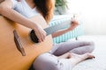 Asian young lesbian couple playing guitar for her lover with love moment in the bedroom surrounded with warm sunlight. Royalty Free Stock Photo