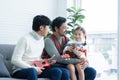 Asian young LGBTQ gay couple playing ukulele and singing with little Caucasian adopted kid in living room at home