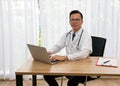 Asian young male happiness doctor typing laptop sitting at desk