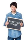 Asian young man with chalkboard showing phrase of semester start Royalty Free Stock Photo