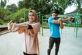 an asian young man and a girl in a veil standing doing warm-up movements before exercising Royalty Free Stock Photo