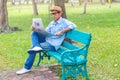 Asian young Man with hat sitting on a wooden bench and reading a newspaper in a park Royalty Free Stock Photo