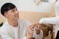 Asian young man kneeling and proposing to his girlfriend with ring