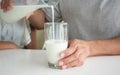 Asian young man pouring milk into glass from modern jug that breakfast for productive morning routine before going to work