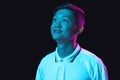 Asian young man& x27;s portrait isolated on dark studio background in neon light. Royalty Free Stock Photo