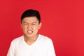 Asian young man's portrait on red studio background. Concept of human emotions, facial expression, youth, sales, ad. Royalty Free Stock Photo