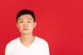 Asian young man's portrait on red studio background. Concept of human emotions, facial expression, youth, sales, ad. Royalty Free Stock Photo