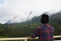 Asian young man in Scottish shirt and black hat hiking at mountain peak above clouds and fog Hiker outdoor.