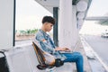 Asian young man sitting on the chair at the airport bus stop and Royalty Free Stock Photo