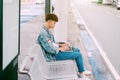 Asian young man sitting on the chair at the airport bus stop and Royalty Free Stock Photo