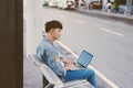 Asian young man sitting on the chair at the airport bus stop and Royalty Free Stock Photo