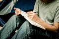 Asian young man sitting is holding a pen writing note of letter memorize memories on book in outside the tent. Loneliness