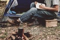 Asian young man sitting is holding a pen writing note of  letter memorize memories on book  in outside the tent. Loneliness Royalty Free Stock Photo