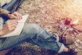 Asian young man sitting is holding a pen writing note of letter memorize memories on book in outside the tent. Loneliness camping Royalty Free Stock Photo