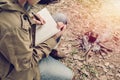 Asian young man sitting is holding a pen writing note of letter memorize memories on book in outside the tent. Loneliness camping Royalty Free Stock Photo