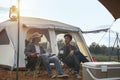 Asian young man two persons sitting enjoy coffee drink near a camping tent in the morning time, coffee drink relaxing on the