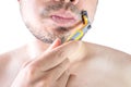 Asian young man using a razor shaving his beard. Do not use cream. on white background and clipping path. Clean face treatment Royalty Free Stock Photo