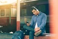 Asian young man using smartphone and listen music waiting train Royalty Free Stock Photo