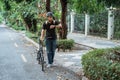 Asian young man walking with folding bike while looking her watch Royalty Free Stock Photo