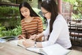 Asian young man and woman sitting pointing studying examining, Tutor books with friends Young students campus helps friend