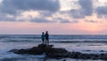 Asian young man and woman standing on a rock watching sunset.
