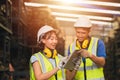 Asian young man and women worker team engineer working help support together using tablet happy smile to work in factory industry Royalty Free Stock Photo