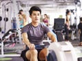 Asian young man working out on rowing machine Royalty Free Stock Photo