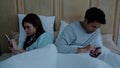 Asian young married couple used smartphone chatting on bed