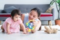 Asian young mother and Caucasian 7 months baby newborn girl playing with development toy and bear doll. Single mom lying on floor Royalty Free Stock Photo