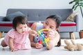 Asian young mother and Caucasian 7 months baby newborn girl playing with development toy and bear doll. Single mom lying on floor Royalty Free Stock Photo
