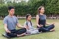 Mother, father practicing doing yoga exercises with child daughter outdoors in meditate pose together