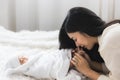 Asian young mother kissing foots of cute newborn baby sleeping. Mother `s day concept