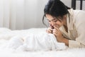 Asian young mother kissing foots of cute newborn baby sleeping. Mother `s day concept