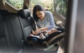 Asian young mother putting her baby son into car seat and fasten seat belts in the car Royalty Free Stock Photo