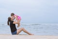 Asian young mother throwing up her baby girl on sandy beach Royalty Free Stock Photo