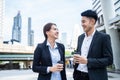 Asian young office businesspeople stand outdoor in city with confident. Formal working partner man and woman hold cup of coffee,