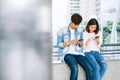 Asian young people are using smartphone and smiling while sitting on free time. Royalty Free Stock Photo