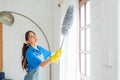 Asian young professional cleaning service woman worker working in the house. The girl cleans the curtain and window. Royalty Free Stock Photo