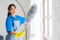 Asian young professional cleaning service woman worker working in the house. The girl cleans the curtain and window. Royalty Free Stock Photo