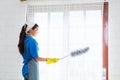 Asian young professional cleaning service woman worker working in the house. The girl cleans the curtain and window. Royalty Free Stock Photo