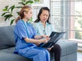 Asian young professional female doctor in blue hospital uniform with stethoscope sitting on sofa couch holding spine xray film Royalty Free Stock Photo