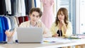 Asian young professional talent male female dressmaker designer seamstress colleague with measuring tape sitting at working table