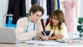 Asian young professional talent male female dressmaker designer seamstress colleague with measuring tape sitting at working table Royalty Free Stock Photo