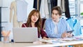 Asian young professional talent male female dressmaker designer seamstress colleague with measuring tape sitting at working table Royalty Free Stock Photo