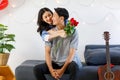 Asian young romantic lover couple female girlfriend holding red roses bouquet hugging cuddling surprising male boyfriend