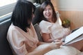 Asian young sisters lovely couple laying on white bed and talking together for online working with laptop in bedroom. Royalty Free Stock Photo