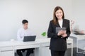 Asian young successful businesswoman wear formal suit standing and holding tablet smiling with confident at office Royalty Free Stock Photo